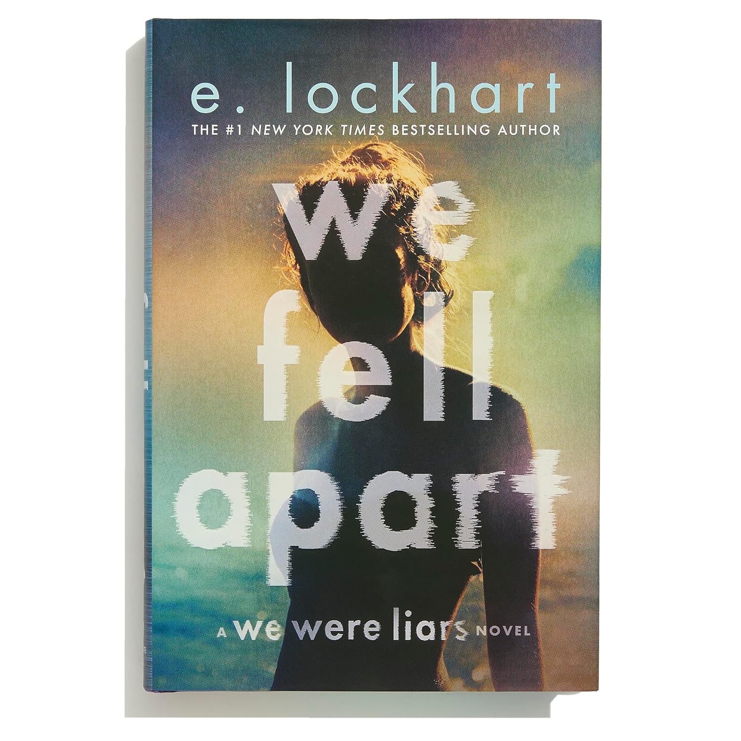 Book cover of 'We Fell Apart' by e. lockhart with a silhouette against a sunset.